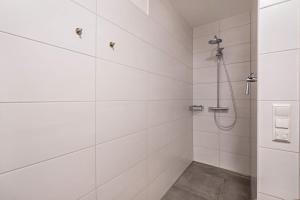 a bathroom with a shower with white tiled walls at Ferienwohnung Rosa in Gilching +12 photos