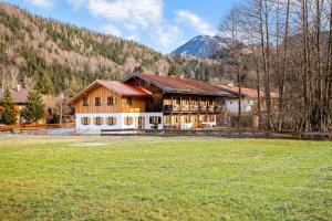 a large house with a field in front of a mountain at Ferienwohnung Uferweg in Fischbachau