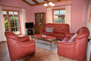 a living room with red leather furniture and a tv at Haus Mövenort in Lütow
