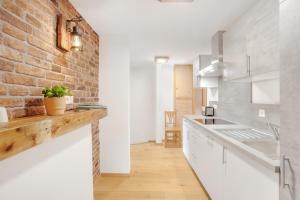 a kitchen with white cabinets and a brick wall at Ferienwohnung Uferweg in Fischbachau +18 photos