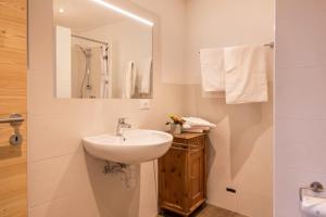 a white bathroom with a sink and a mirror at Nigglhof Apartment Maria in Redagno