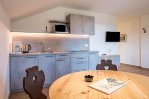 a kitchen with a wooden table with chairs and a wooden tableablish at Nigglhof Apartment Maria in Redagno +13 photos