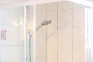 a shower with a shower head in a bathroom at Jolie maison mitoyenne in Concarneau +16 photos