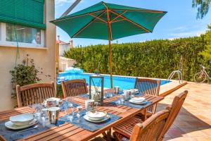 a wooden table with a green umbrella on a patio at Dosmadres7 in Llucmajor
