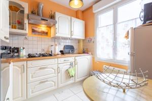 a kitchen with white cabinets and a table at Jolie maison mitoyenne in Concarneau