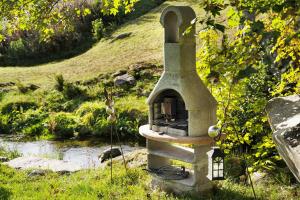 a stone oven sitting in the grass next to a river at Haus Löwen in Forbach