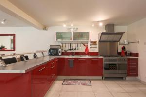 a kitchen with red cabinets and a stove top oven at Gîte Les Galets Blancs in Trébeurden