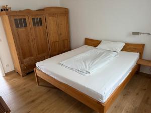 a bedroom with a bed and a wooden cabinet at Hofberg Villa - Appartment in Landshut