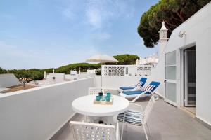 a patio with a white table and chairs on a balcony at Casa Harlequin in Vale do Lobo