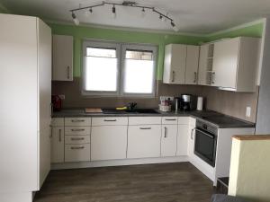a kitchen with white cabinets and a window at Ferienwohnung Wiesenblick in Plettenberg