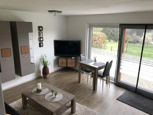 a living room with a television and a table and chairs at Ferienwohnung Wiesenblick in Plettenberg