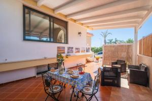 a dining room with a table and chairs on a patio at Malva House in Villa Con Piscina in Torre Lapillo
