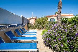 a row of blue lounge chairs next to purple flowers at Malva House in Villa Con Piscina in Torre Lapillo