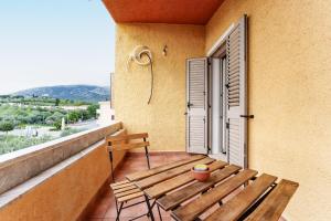 a wooden table and chairs on a balcony with a window at Cozy And Cool Flat in Orosei