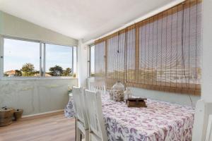a dining room with a table and chairs and a window at Bisa's house in Estoril