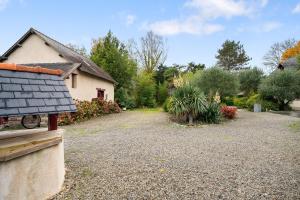 a yard with a house and a gravel driveway at Gîte La Malcotais in Noyal-Châtillon-sur-Seich