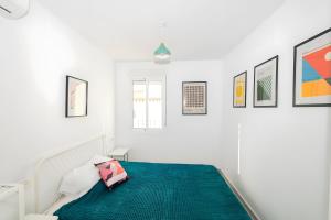 a white bedroom with a bed with a green blanket at Casa de Arte in Torrox