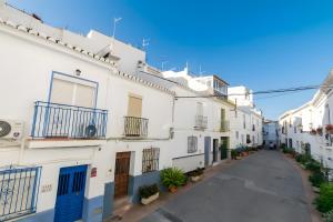 an alley with white buildings and a blue door at Casa de Arte in Torrox