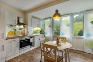 a kitchen with a table and chairs and windows at Hof Helmenhube 1 in Oberzent