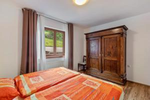a bedroom with a bed and a wooden cabinet and a window at Hof Helmenhube 1 in Oberzent