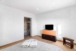 a white bedroom with a bed and a tv at Finca Eva in Granadilla de Abona