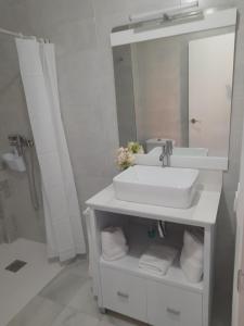 ein weißes Badezimmer mit Waschbecken und Spiegel in der Unterkunft Ático Bulevar in Macael + 8 Fotos