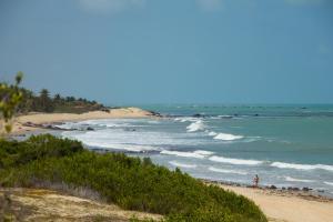 a beach with a group of people standing on the sand at Pousada Costa Prestige in Touros