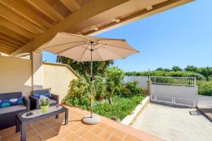 a patio with a couch and an umbrella at Estrella de mar verde in Port d'Alcudia