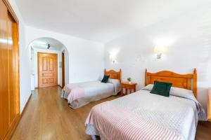 two beds in a room with white walls and wooden floors at Apartamento residencial Fénix in Roquetas de Mar +16 photos