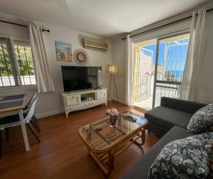 a living room with a couch and a tv and a table at Casa Blanca in Torrox Costa