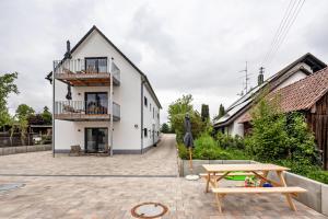 a white house with a patio and a table at Fewo Parkside S3 - 8Min Legoland in Günzburg
