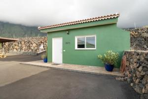 a green house with a white door and a stone wall at Loft de Tato in Frontera