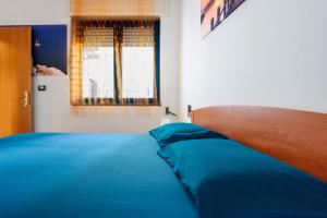 a bedroom with a bed with blue sheets and a window at Dimora Giusy in Otranto