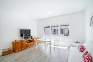 a white living room with a table and a tv at El Rincón de Mónica in Agaete