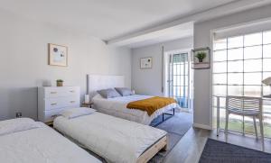a bedroom with three beds and a window at Costa Nova Ocean View in Gafanha da Encarnação