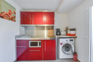 a kitchen with red cabinets and a washing machine at Fewo Trudi in Grabenstätt