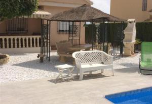 a patio with a white bench and a gazebo at Casa Cuesta in Bolnuevo