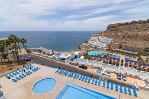 a view of a resort with a pool and the ocean at Stunning Sunset Ocean View Apt in Taurito