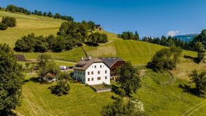 an aerial view of a house on a green hill at Apartments Perfila Dolomitenblick in Valdaora