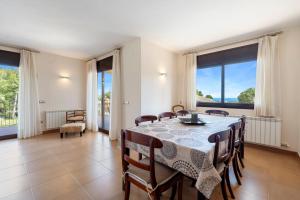 a dining room with a table and chairs and windows at Casa Tico in Roda de Bará