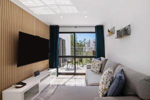 a living room with a couch and a flat screen tv at Amazing Oura Beach Apartment in Albufeira