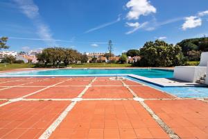an empty swimming pool with a red brick floor and a blue sky at Amazing Oura Beach Apartment in Albufeira
