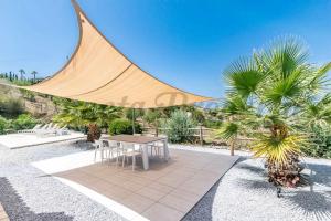 a patio with a table and some palm trees at Casa Arco Iris in Cómpeta