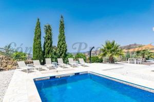 a swimming pool in a villa with palm trees at Casa Arco Iris in Cómpeta