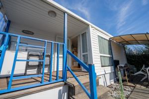 a front porch of a tiny house with blue railings at Mobilehome 4 personnes in Les Mathes +9 photos