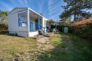 a small white house with a porch and blue railing at Mobilehome 4 personnes in Les Mathes