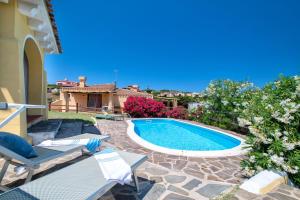 a swimming pool in a yard with chairs and a house at Villa Azzurra in Stintino