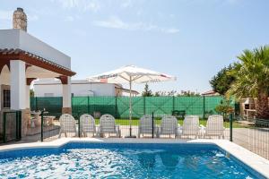 a swimming pool with chairs and an umbrella at Las Alas del Sol in Vejer de la Frontera