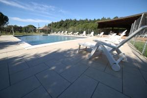 a group of chairs sitting around a swimming pool at Il Vignone - Castagneto Carducci in Castagneto Carducci