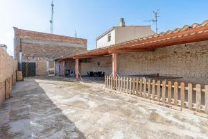 a brick building with a fence in front of it at La Garrofera in Aldover